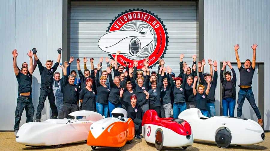 Echipa Velomobile World în fața halei metalice Frisomat din Breaza, alături de velomobile produse în România