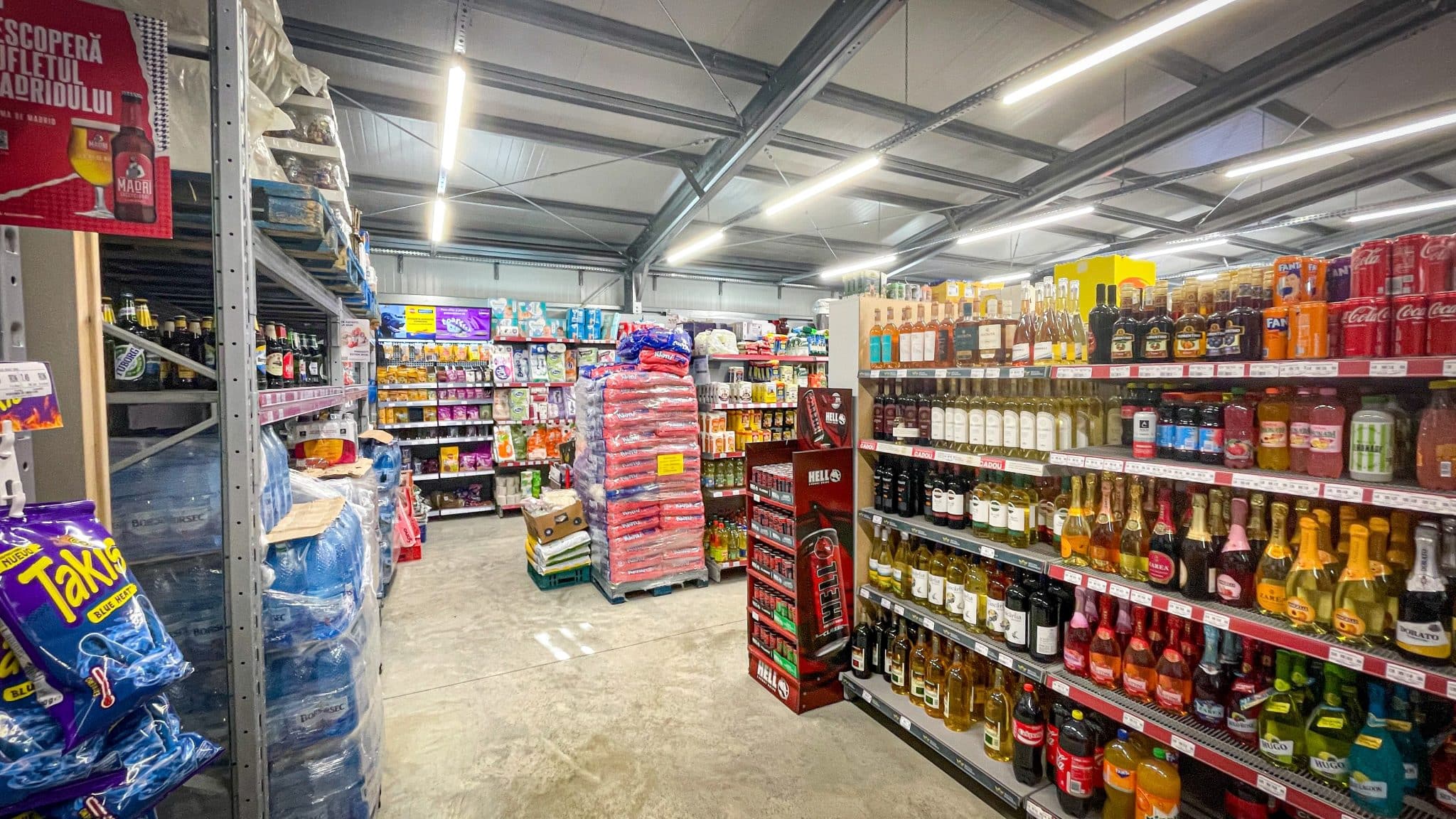 Zonă comercială cu rafturi și produse în supermarketul MADVIR din hala Frisomat