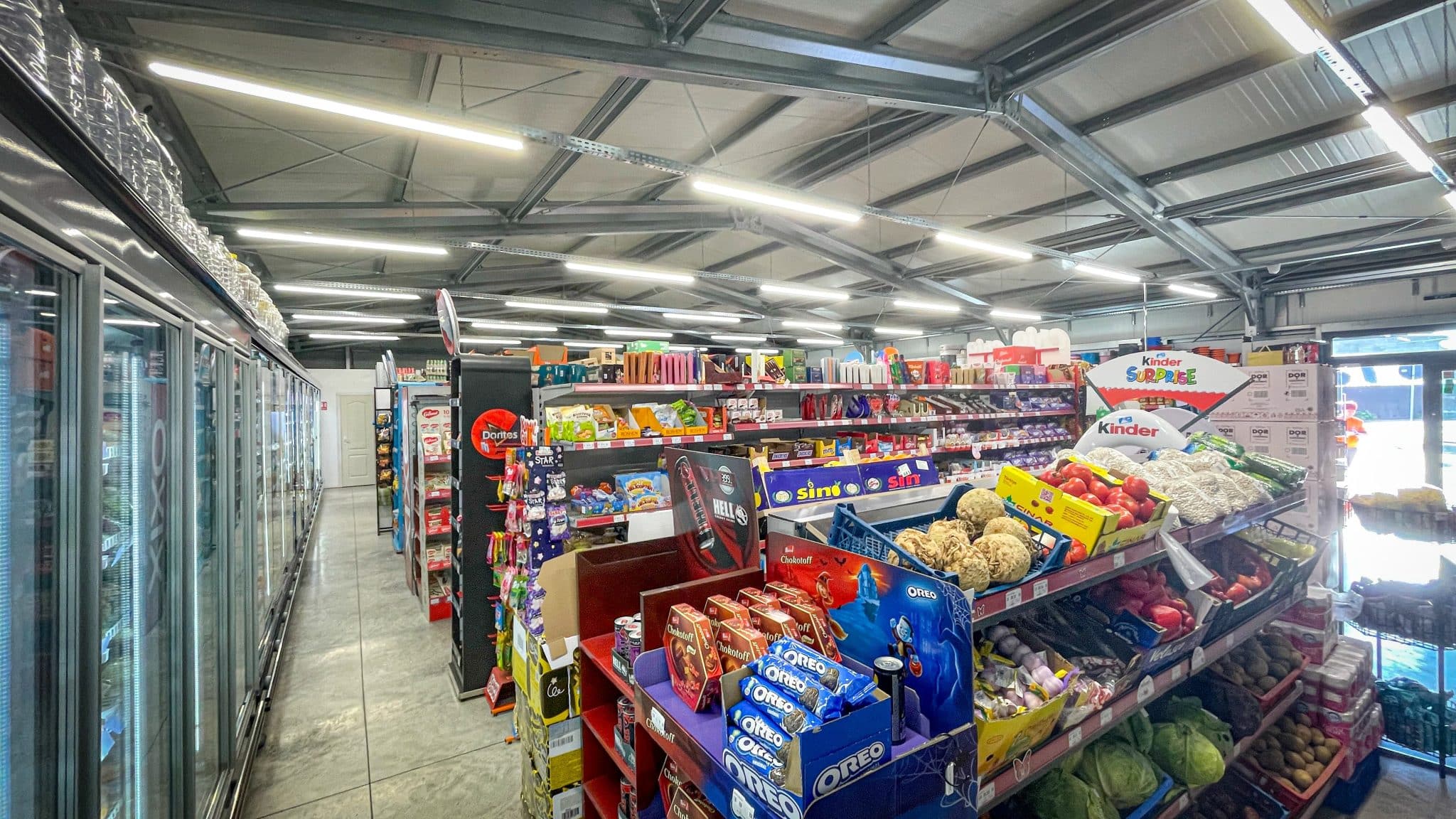 Interiorul supermarketului din Urechești, cu rafturi comerciale și structură metalică aparentă